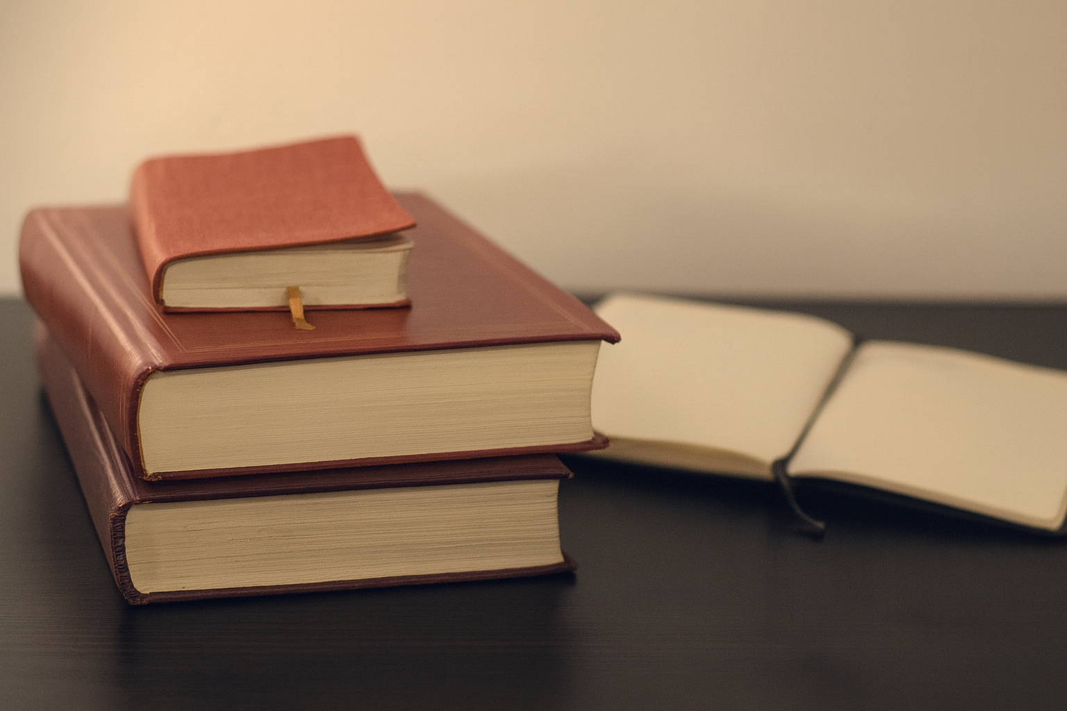 selective focus photography of three books beside opened notebook